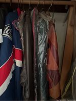 Photo showing various men's jackets including a Patriots jacket and leather jackets hung on a closet rod.