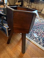 Side view of the hexagonal wooden planter on angled legs showing dark stained wood and angular leg design.