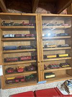 Full view of wooden display cabinet with glass doors housing all train cars