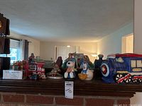 Front view of various ceramic items including two trains, Snoopy, a goose, and a gnome on a wooden ledge in front of a mirror.