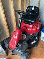 Front three-quarter view of red Craftsman ride-on mower showing deck, steering column and front tire