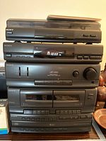 Sony stereo system vertical stack with multiple components and two small speakers visible on sides