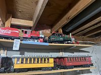 Two wooden basement shelves holding G scale locomotives and cars