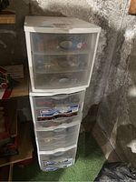 Six-drawer white plastic organizer containing various train scene accessories.