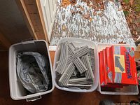 Three plastic bins containing boxed switches, loose track pieces and unboxed switch mechanisms.