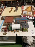 Photo showing arranged Western village accessories including animals, buildings, wagon, and signs.