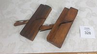 Two antique wooden woodworking planes lying flat on a table showing general shape and mechanism.