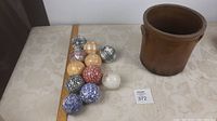 Eleven patterned balls arranged with the stoneware crock