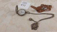 Open pocket watch with chain and leather band on cloth