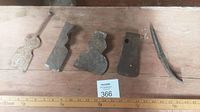 Wide shot of five primitive tool heads showing varying shapes and sizes arranged horizontally on wooden surface.