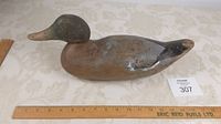 Side profile of the antique wooden duck decoy showing the painted head and body with wear and a loose head fitting.