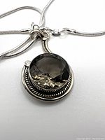 Close-up photo of the pendant showing the faceted round smoky topaz set in a sterling silver mount with rope detail and attached to the silver chain.