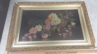 Framed antique oil painting of roses in a basket, showing entire artwork and frame.