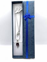 Full view of the amethyst pendant on the chain inside a blue gift box with a blue ribbon bow.