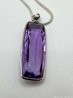 Close-up of rectangular faceted purple gemstone bezel set in silver