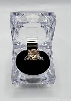 Ring in clear acrylic box viewed from front showing center stone and box