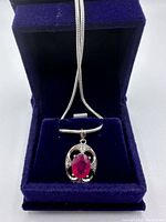 Necklace displayed inside blue velvet box, chain draped over lid