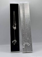 Sterling silver heart pendant necklace displayed inside a decorative silver gift box with textured pattern and silver bow.