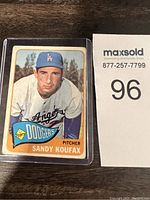 Front view of the 1964 Sandy Koufax Topps baseball card in protective case showing player image, team, and position.