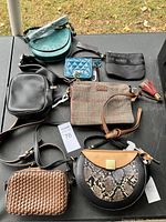 Seven various bags and wallets laid out on a dark table, showing different materials, colors, and styles.