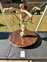 Full view of the natural wood bird/perch with round wooden base and hanging chain with bells