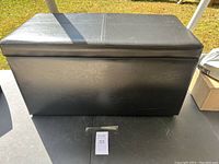 Black leather rectangular storage bin closed, showing the smooth top with sewn lines in rectangular pattern.