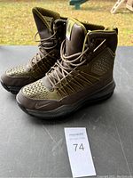Front and side angle view of pair of olive green Nike boots with lace-up closure and Nike logo on the sole.