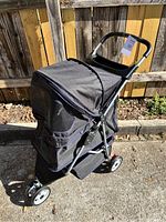 Full view of black pet stroller showing four wheels, mesh windows, and fabric canopy.
