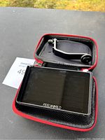 Feelworld camera monitor with mounting arm inside red carrying case on table surface.