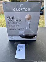 Photo of original box showing brand, capacity (81 ounces), and suitability for wine, whiskey, or other beverages. Box indicates unique glass design.