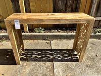 Front view of the natural wood accent table showing rectangular structure and carved sides.