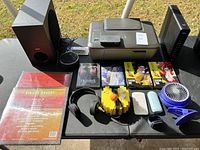 Photo shows Canon MX430 printer, Sony subwoofer, headphones, Sega Saturn video games, blue clip-on fan, yellow electronic joystick-like device, and white electronic accessories.