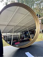 Front view of large round mirror showing gold/brass colored frame and reflective surface.