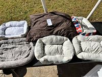 Overview of six pet beds outdoors on pavement, showing sizes and colors including brown, grey, white, and patterned edge designs
