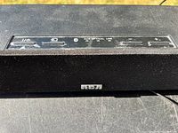 Close up of top panel inputs and controls of RCA soundbar including USB, auxiliary, optical, line, and volume controls with RCA logo on front fabric.