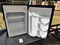 Open view of the refrigerator interior showing freezer compartment, wire shelves, and door storage compartments with cup holders
