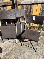 Set of 4 folding chairs arranged with one chair in front showing seat and backrest, others stacked behind.