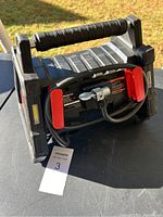 Three-quarter view of entire inflator showing handle, housing and coiled hose.