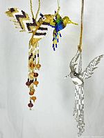Two beaded hummingbird ornaments hanging, showing colors, details, and dangling bead strands.
