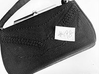 Top view of the black purse showing the textured swirl pattern and silver framing.