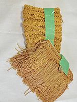 Photo of golden fringe trimming showing woven yarn and tassels, illustrating the texture and color.