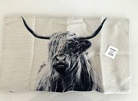 Front view of Highland cow printed cushion cover on beige fabric background, showing the full image and texture.