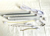Three LED grow light bars with cables and mounting brackets on white surface