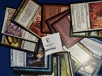 Loose assorted Magic the Gathering cards on a blue surface showing multiple cards of different colors and text boxes