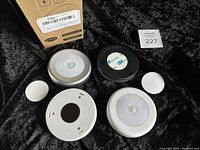 Overview of the five round nightlights displayed with their backsides showing battery compartments and adhesive pads alongside the original box.