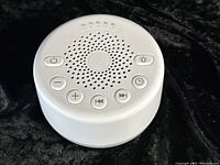 Top view of white noise machine showing speaker grille and control buttons on top surface.