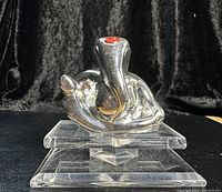 Front view of silver elephant paperweight on clear acrylic base against black background.