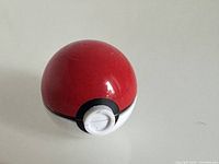 Closed view of the item showing the spherical red, white, and black Poké Ball design