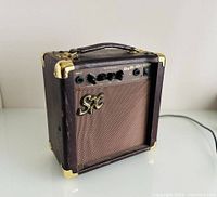 Front and left angle view of brown SX amp showing front control panel, handle, and corner guards.