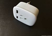 Front view of the white travel plug adapter showing two USB ports and compatible socket slots for plugs.